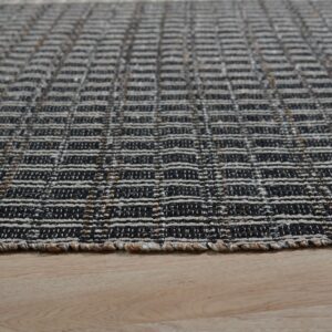 Black and off-white flatweave rug with a horizontal textured grid pattern resting on light hardwood floors.