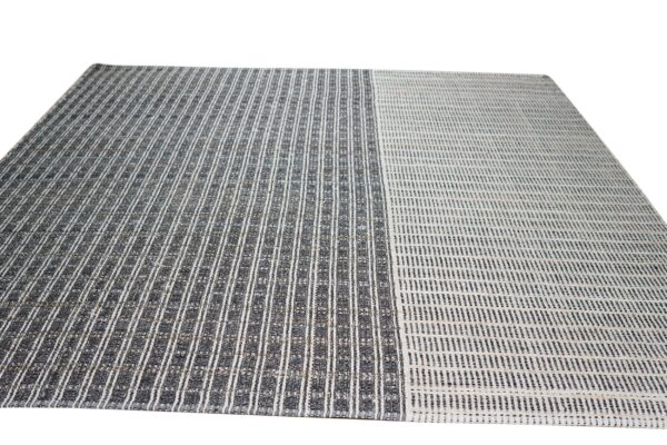 Striped flatweave rug featuring a bold dark gray section next to a lighter off-white striped section.