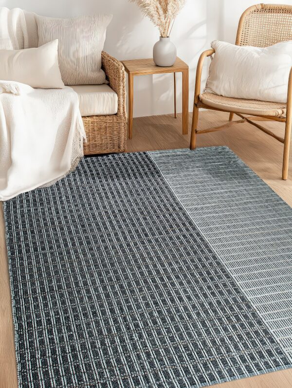 A flatweave rug with dark vertical and light horizontal stripes anchors a room with rattan furniture.