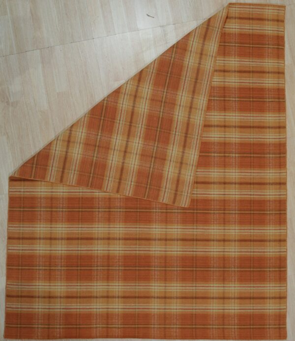 Orange and tan plaid rug displayed on light wood flooring with one corner folded back.