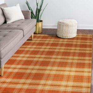 Orange and yellow plaid rug sits under a gray sofa and woven pouf on dark wood floor.
