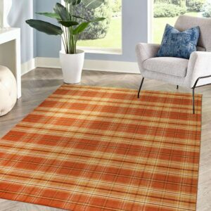 Low profile orange plaid rug placed on light wood floors beside a gray armchair and a large plant.