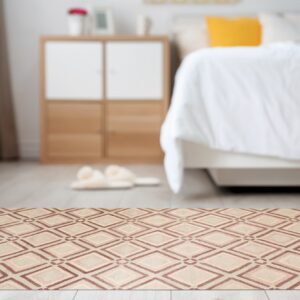 A low profile rug with a brown and tan geometric diamond pattern sits on light flooring in a bright bedroom.