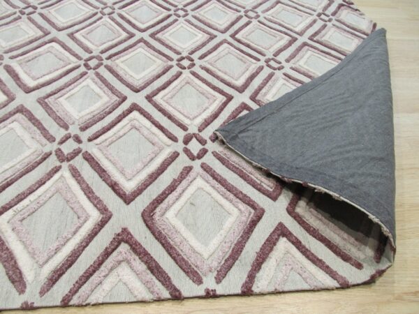 Low pile rug with textured mauve and white geometric diamonds on a light gray base; corner is folded showing gray backing.