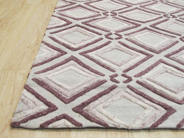 Raised purple and pink diamond patterns cover a light grey rug lying on blonde wood flooring.
