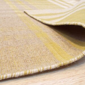 Close-up of a low-pile yellow and beige striped rug folded over on light wood flooring.
