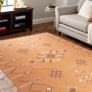 Orange flatweave rug with white and brown geometric patterns covers a living room floor beside a gray armchair.