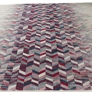 Flat-weave rug featuring a central red and blue chevron design fading out to a cream border.