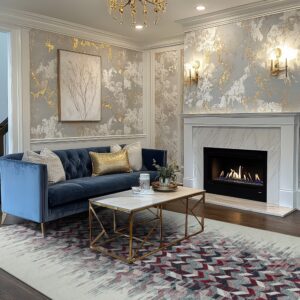 Geometric red and gray low-pile rug beneath a marble-top gold coffee table and blue velvet sofa.
