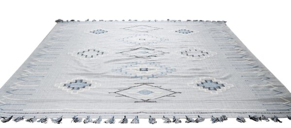 Light gray flatwoven rug featuring a geometric pattern of blue and white diamonds and blue edge tassels.