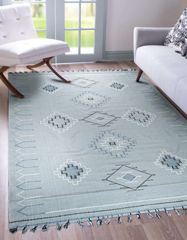 Low-pile blue rug with contrasting geometric patterns in a room with wood flooring and modern seating.