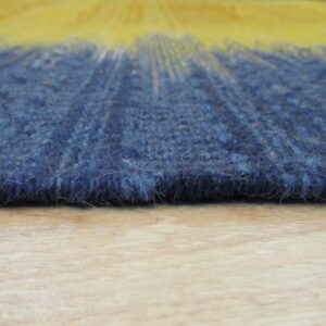 Shaggy blue and yellow ombre rug texture shown close-up on a light wood surface.