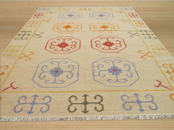 Beige low-pile rug featuring geometric octagonal designs in red, blue, and yellow on a light wood floor.