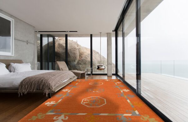 Bright orange flatweave rug with geometric patterns on dark wood floors in a modern bedroom with large glass windows.