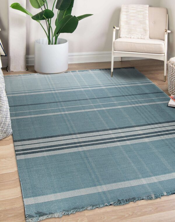 Blue-green flatweave rug featuring a plaid pattern of light and dark gray stripes in a living space.
