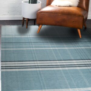 Blue and gray plaid rug lies on dark wood floors beside a leather chair and potted plant.