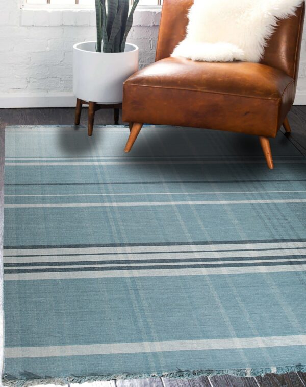 Blue and gray plaid rug lies on dark wood floors beside a leather chair and potted plant.