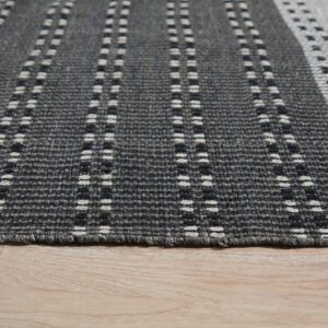 Textured gray rug with dashed vertical stripes and geometric patterns rests on a light wood floor.