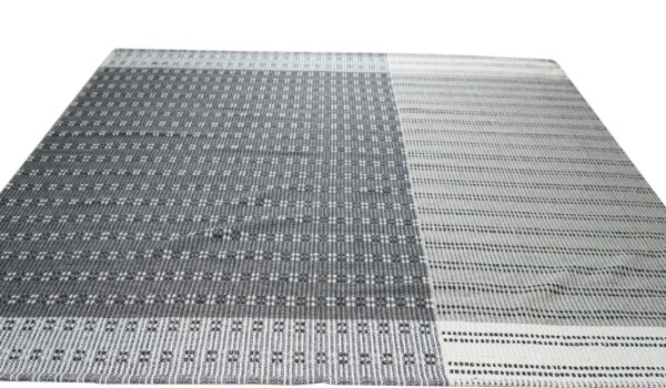 Gray and white low-profile rug with geometric patterns in contrasting dark and light vertical blocks.