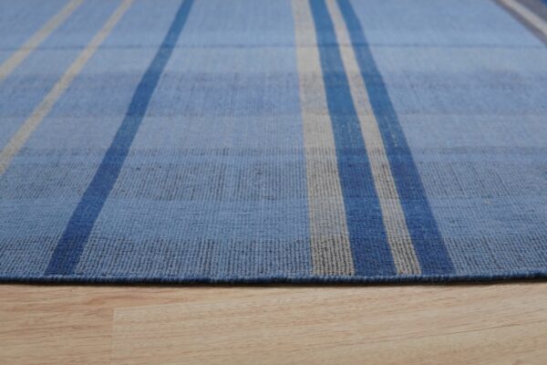 Blue striped low-pile rug featuring gray and dark blue accents on light wood flooring.