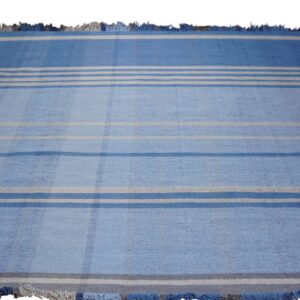 Blue rug with visible low texture and a striped pattern featuring white, gray, and dark blue bands.