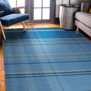 A blue and gray plaid flatweave rug sits on hardwood floors near a wooden chair and gray sofa.