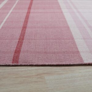 Pink, white, and red plaid low-pile rug resting on light wood-look flooring.