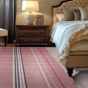 Pink, white, and gray plaid rug lies on hardwood floors next to a dark wood nightstand and tufted bed.