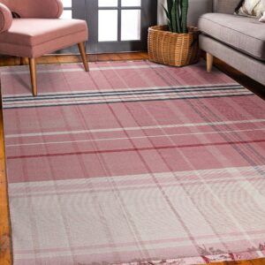A pink and white plaid flatweave rug on a wood floor between a pink chair and a gray sofa.