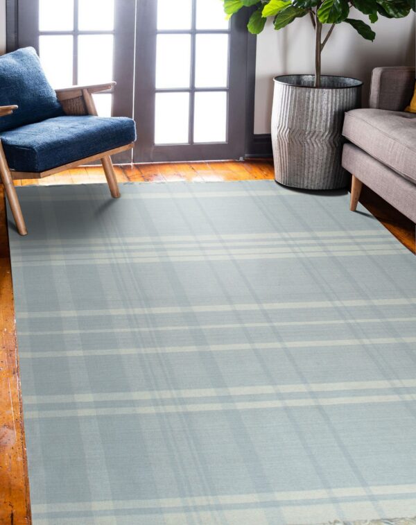 Pale blue plaid rug with cream stripes covers wood floors next to an armchair and sofa.