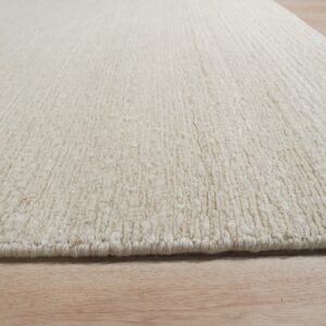 Textured off-white rug with thick vertical ribs resting on light natural wood planks.