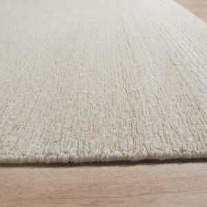 A chunky cream rug with visible ribbed texture rests on natural light wood plank flooring.