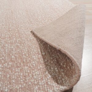 Textured pale pink and white speckled rug partially rolled back, showing the backing on light wood flooring.