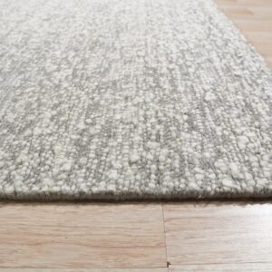Textured gray and white rug with chunky pile shown from a low angle on light wood flooring.