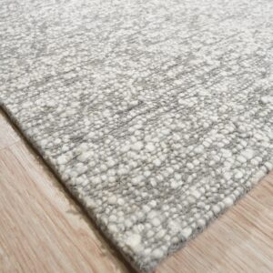 Mottled gray and white rug with a chunky, textured surface rests on light wood flooring.