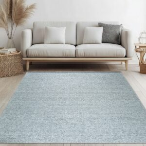 A pale blue textured rug sits under a cream sofa with a wooden base on light plank flooring.