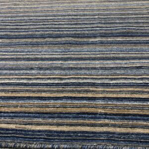 A ribbed rug with horizontal stripes in shades of blue, tan, and gray on light wood flooring.