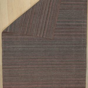 Low-pile rug with horizontal variegated gray and reddish-brown stripes, folded on light wood.