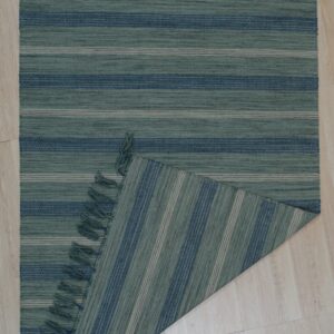 Teal and navy striped low-pile rug with tassels, folded over to show vertical stripes on the reversible side.