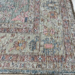 Textured pile rug in faded beige, rust, and teal features a distressed abstract pattern on wood floors.