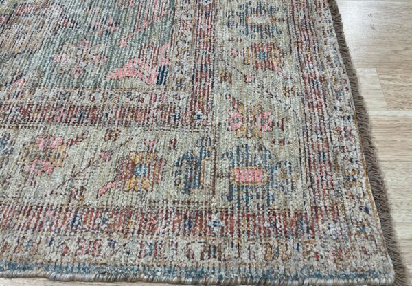 Textured pile rug in faded beige, rust, and teal features a distressed abstract pattern on wood floors.