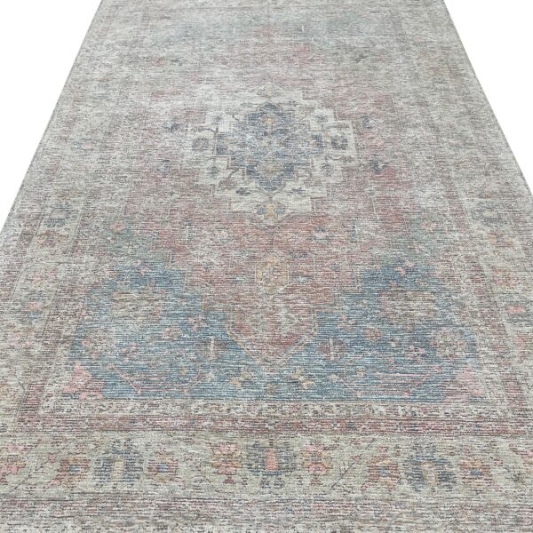 Distressed low-pile area rug featuring a subtle traditional medallion design in muted beige, blue, and dusty rose.