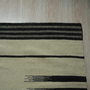 Light beige flatweave rug with thick dark brown stripes and dashed linear patterns on light wood flooring.