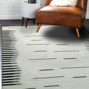 Black and cream flatweave rug with dash patterns and ikat stripes styled with a brown leather chair.