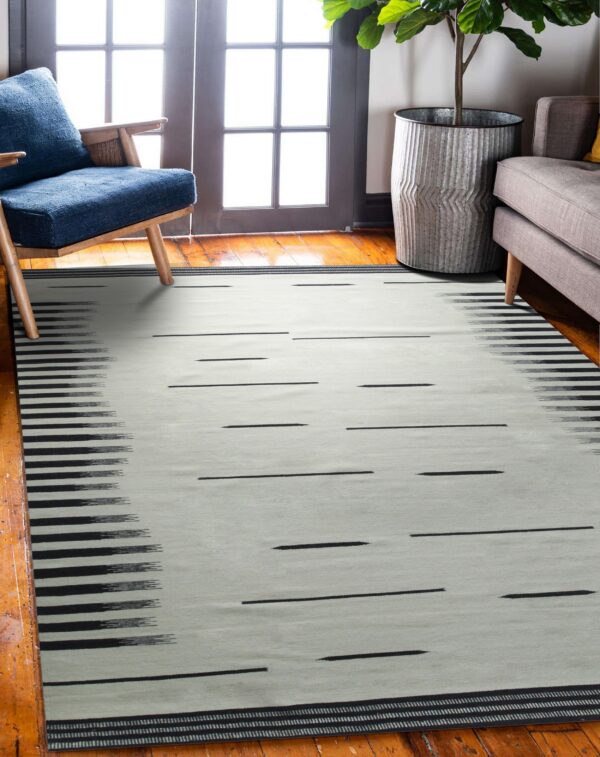 Black and gray patterned rug featuring dashed lines and stripes is placed on hardwood flooring.
