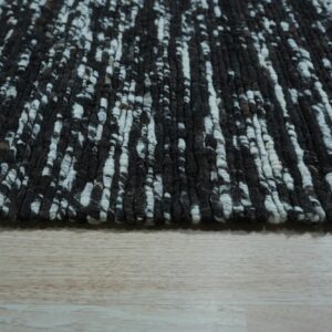 High-pile rug featuring a black and white mottled, vertical texture on light wood planks.