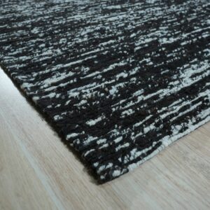 Textured black and white rug featuring a chunky horizontal streaky pattern on light wood flooring.
