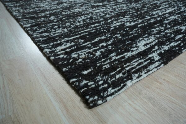 Textured black and white rug featuring a chunky horizontal streaky pattern on light wood flooring.