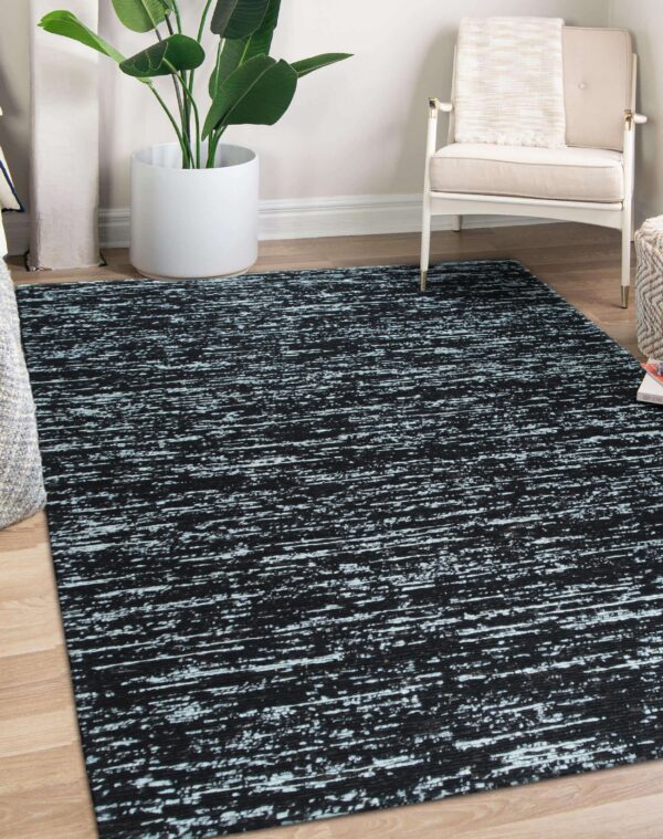 Abstract black rug featuring distressed horizontal light blue lines rests on a wood floor in a corner setting.