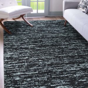 Black and white streaky abstract rug lies beneath a white chair and gray sofa on light wood floors.